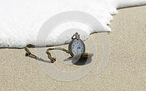 Vintage pocket watch is on the sand.