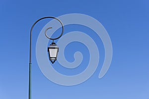 Vintage polelight, white glass and black body lamp on black steel with circle on the top, under deep blue sky background