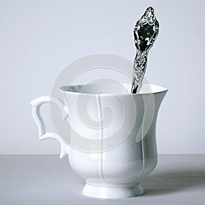 Vintage porcelain cup with silver spoon on white background. 3d