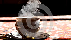 Vintage porcelain tea time on turkish carpet, black tea with smoke in a china cup and saucer on the sunlight, Hot steam