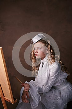 Vintage portrait of artist girl. child in white dress paints picture