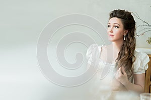 Vintage portrait of beautiful woman with long hair in white dress, looks away