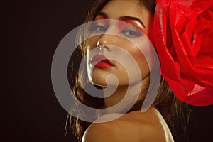 Vintage portrait of fashion glamour girl with red flower in her hair, over black. Studio shot