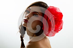 Vintage portrait of fashion glamour girl with red flower in her hair, studio shot.