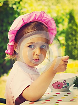 Vintage portrait of little girl eats with appetite