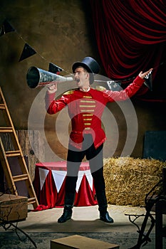 Vintage portrait of male retro circus entertainer expresses rejoice and announces start of show over dark retro circus