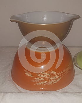 Vintage Pyrex Bows stacked one on top of upside down bowl 2 dufferent patterns orange brown