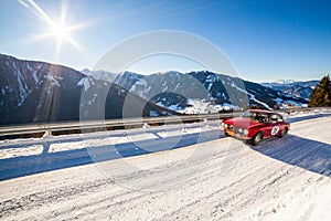 Vintage racing car driving classic rally on snow covert road