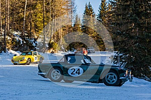 Vintage racing car driving classic rally on snow covert road