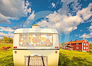 Vintage rear of a caravan in front of a typical old wooden farm house in Smaland, Sweden