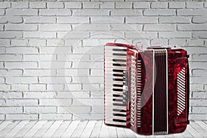 Vintage red accordion on brick wall background