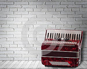 Vintage red accordion on brick wall background