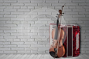 Vintage red accordion and violin on brick wall background