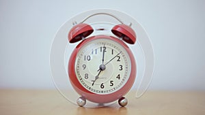 A vintage red alarm clock plays the alarm when dial needle gets to 7 o`clock.