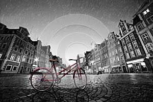 Vintage red bike on cobblestone historic old town in rain. Wroclaw, Poland.