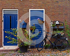 Vintage red bricks House faÃÂ§ade with blue doors and flowers photo