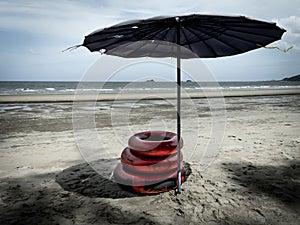Vintage red buoys on the beach beside old dark umbrella with nobody