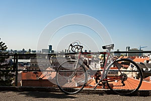 Vintage red city bicycle locked to the metal fence with view over Zagreb. Old red road bicycle.