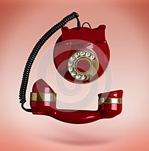 Vintage red corded telephone flying in air on color background