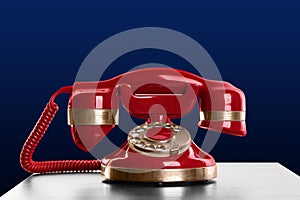 Vintage red corded telephone on table against blue background