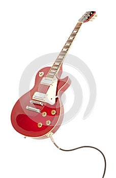 Vintage red electric solid body guitar plugged in.