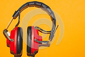 Vintage red headphones on yellow background. classic earphones