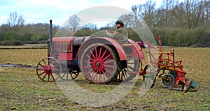 Vintage red International 1930`s tractor ploughing field.