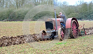 Vintage red International 1930`s tractor ploughing field.