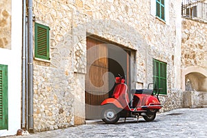 Vintage red motor scooter parked in historic spanish village