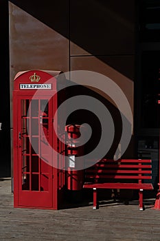 Vintage red phone booth and a wooden bench situated in front of a brick building