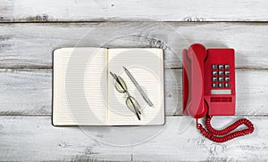 Vintage red phone and notepad with pen and reading glasses on ru