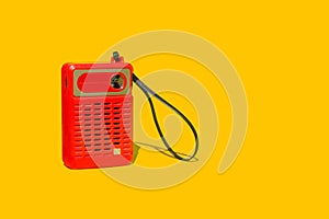 A vintage red portable radio on a yellow background