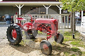 Vintage red tractor beside the historical Marineau farm in Laval