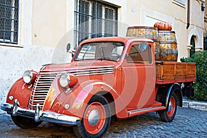 Vintage red van with old wooden barrels of wine