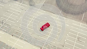 Vintage red vehicle, old fire engine equipped with tools for firefighting tasks, driving on empty parking. Aerial shot