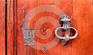 Vintage red wooden door with metallic doorhandle and keyholes