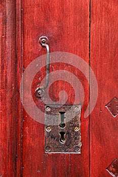 Vintage red wooden door with metallic handle and keyholes