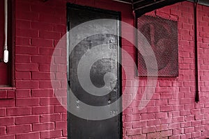 A vintage retro black steel painted door red brick wall and vent