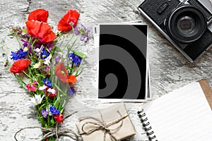 Vintage retro camera with blank photo frame and wildflowers bouquet with lined notebook and gift box