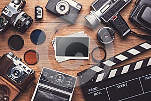 Vintage retro camera with clapboard and old photos on wooden background, clipping path