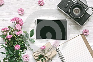 Vintage retro camera and pink rose flowers bouquet with blank photo frame, lined notebook and gift box