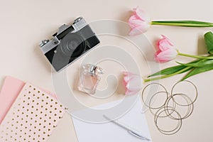 Vintage retro camera and pink tulip flowers with blank notebook on beige background. Feminine blogger flat lay. top view. Spring