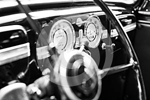 Vintage retro car interior, steering wheel, dashboard, black and white, closeup