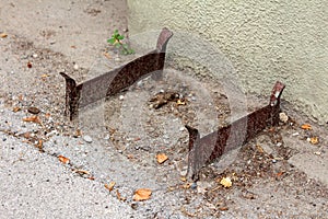 Vintage retro iron shoe and boot mud scrapers mounted on concrete floor outside of family house surrounded with sand and dirt