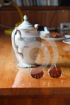 An vintage retro old white teapot, sunglasses on a wooden table in the country summer cottage