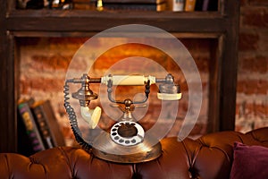 Vintage retro phone with rotary dial in interior on the brick wall and wooden shelves.