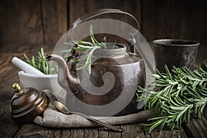 Vintage retro teapot, bunch of fresh rosemary herbs, cup of healthy herbal tea and mortar.