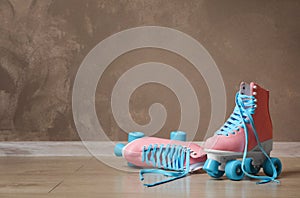 Vintage roller skates on floor near brown wall
