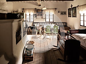 Vintage room with bed, cradle, furnace, table and chairs in old rural house. Sepia style image