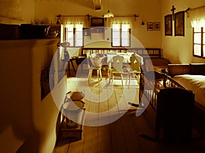 Vintage room with bed, cradle, furnace, table and chairs in old rural house. Sepia style image